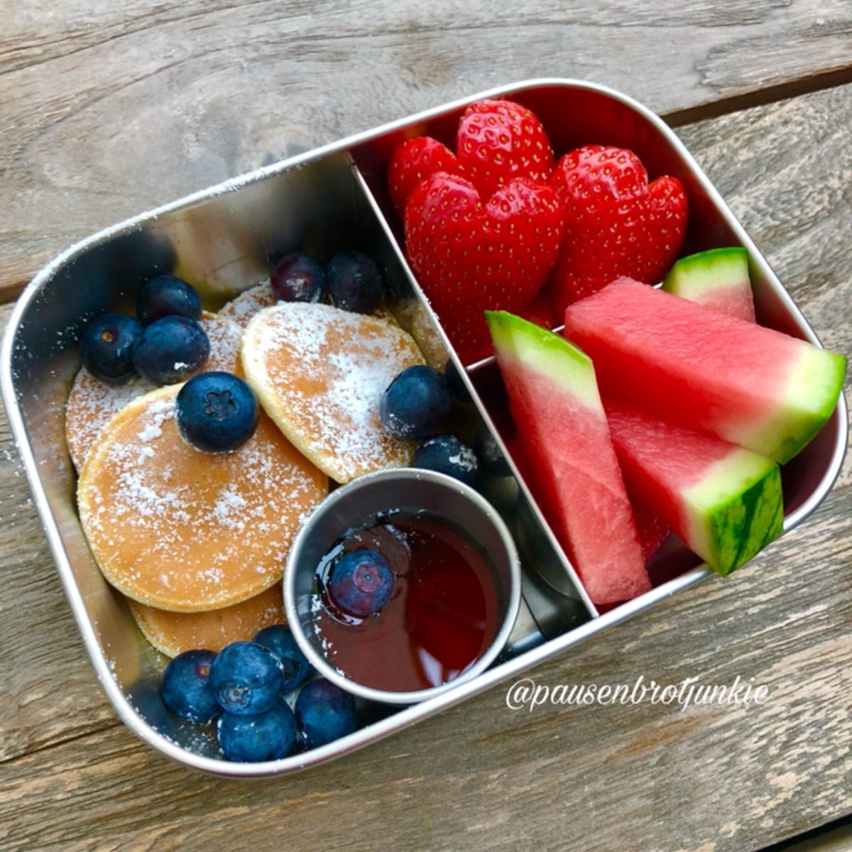 Mini pancakes and blueberries, strawberries, watermelon slices in a kid's stainless steel bento lunchbox for snack time