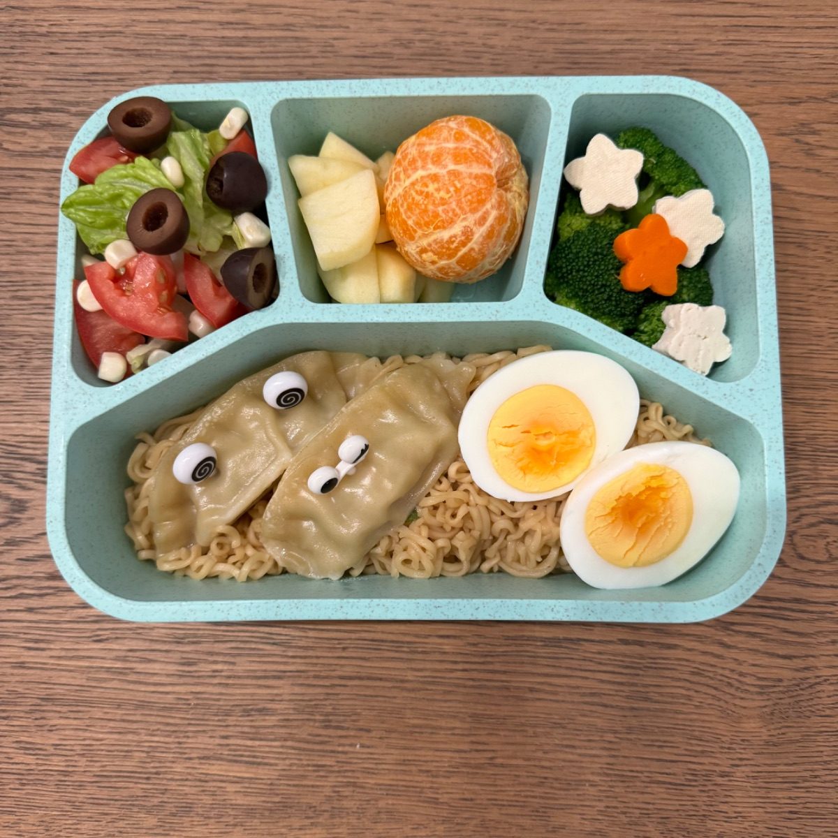Lunchbox filled with long noodles, vegetables, and sesame seeds symbolizing long life for New Year