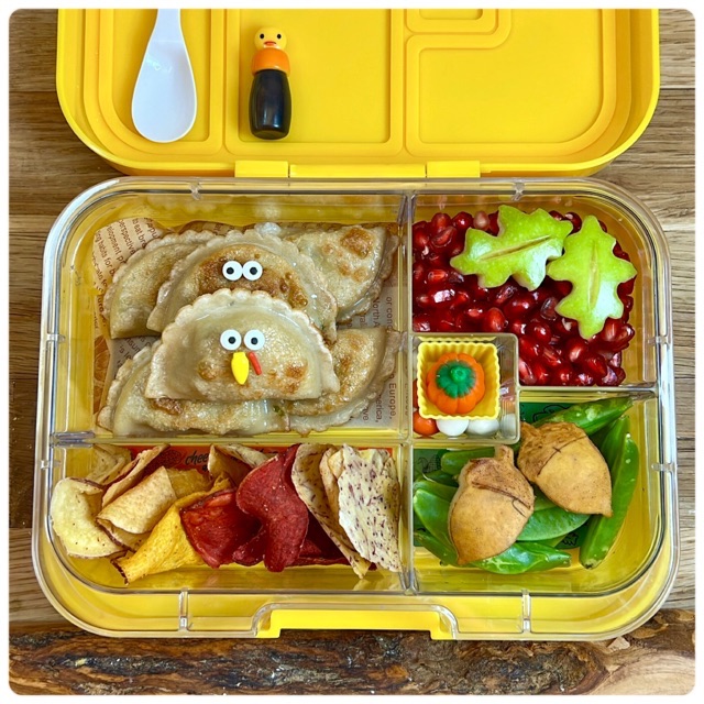 Turkey-shaped raviolis and Thanksgiving food in a bright yellow lunchbox for a kid's lunch at school.