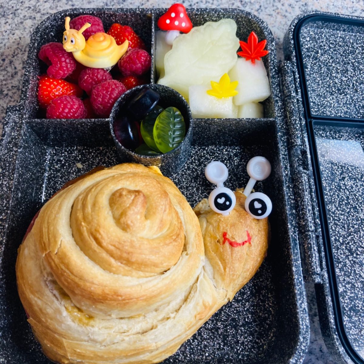 Huge snail pizza rollup in a kid's yumbox lunchbox