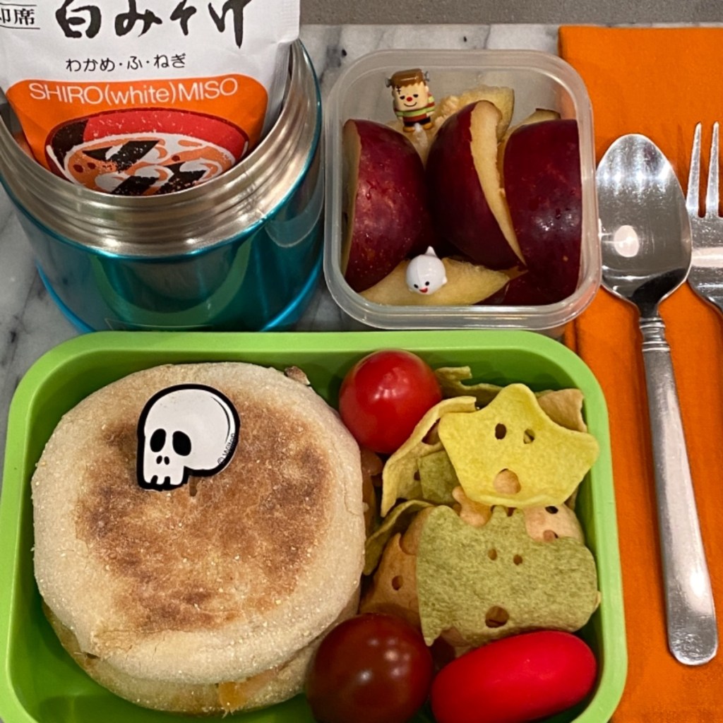 a warm miso soup paired with a unique artichoke-salmon English muffin sandwich for a kid's lunch at school
