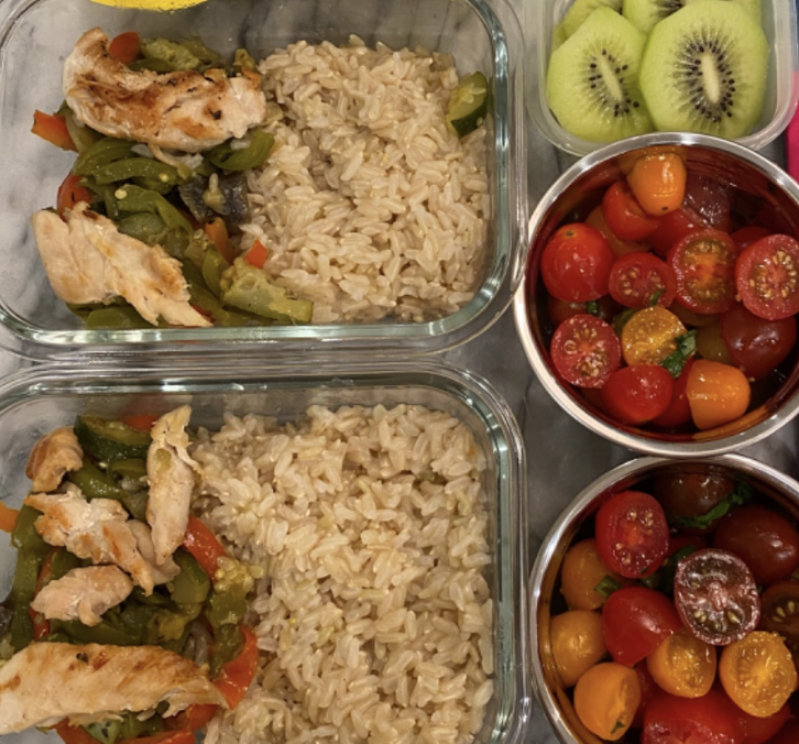 Chicken and veggies on top of brown rice. Cherry tomatoes, and kiwi on the side. Lunch for two kids.