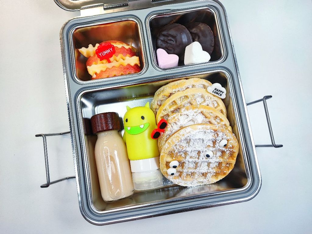 Fresh smoothie, fruits and waffles in a kids' stainless steel lunchbox.