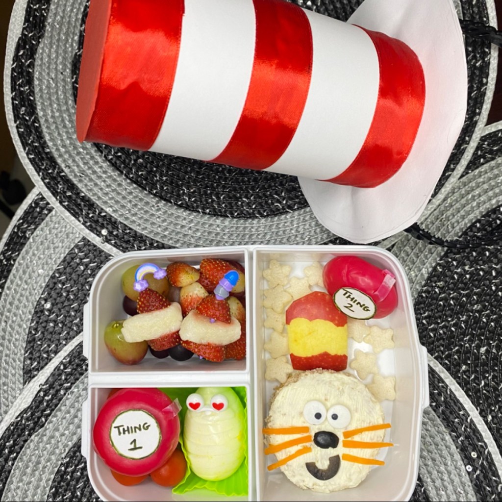 Kids lunchbox featuring a Cat in the Hat-themed sandwich with red-and-white stripes and vegetable whiskers, inspired by Dr. Seuss.
