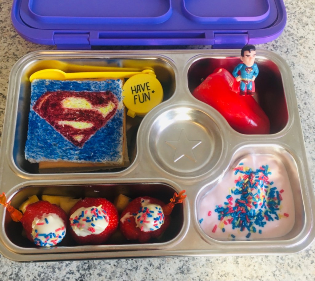 Superman logo sandwich in a kids’ lunchbox with colorful sides, fun superhero-themed meal idea