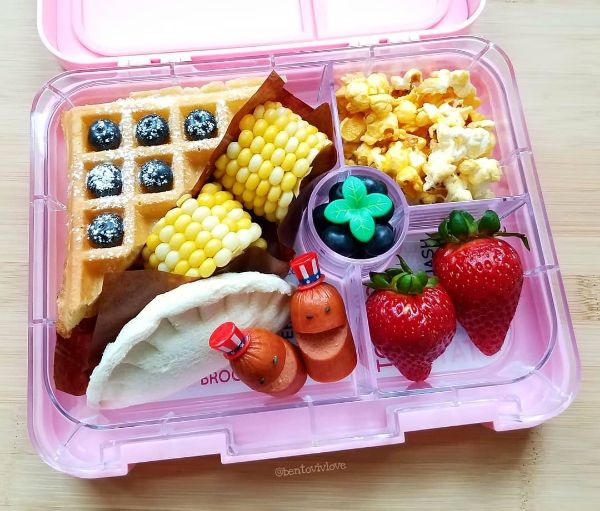 An Independence Day-themed lunchbox packed with American summer favorites including mini corn on the cob, crispy chicken wings, and fresh watermelon bites. This patriotic meal idea is perfect for celebrating July 4th at school or on a picnic. Explore more kid-approved, festive lunchbox inspiration now on Teuko.com.