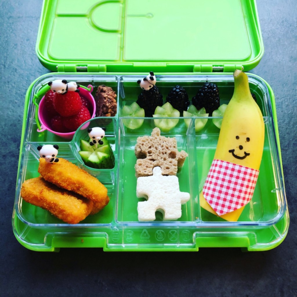 Puzzle shaped sandwiches in a kid's lunchbox with a smiling banana