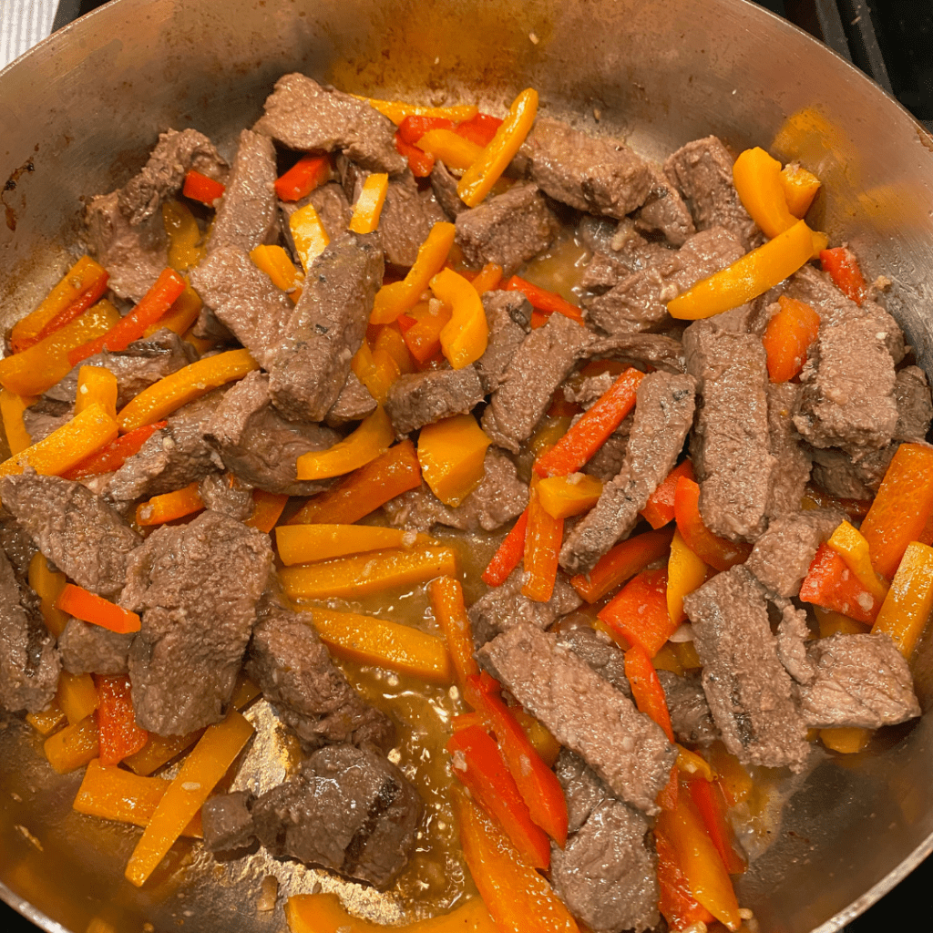 Beef steaks cooked with sliced colorful bell peppers in a pan, ready for kids and teens school lunch meal prep by Teuko.