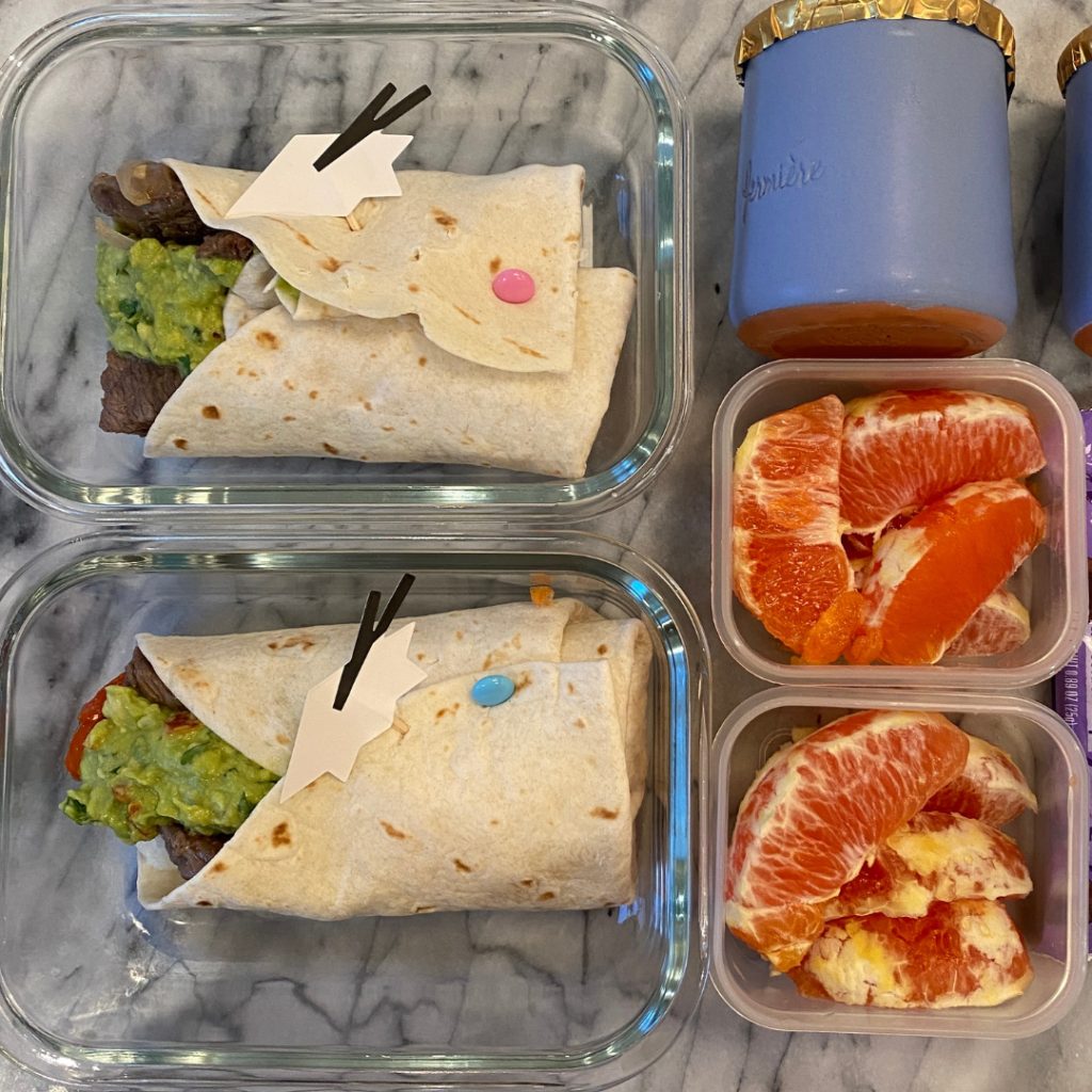 Two kids’ lunchboxes featuring homemade burritos with cilantro lime rice, seasoned beef, cooked bell peppers, and guacamole, accompanied by vanilla yogurt and a Cara orange for dessert - a healthy school lunch by Teuko.