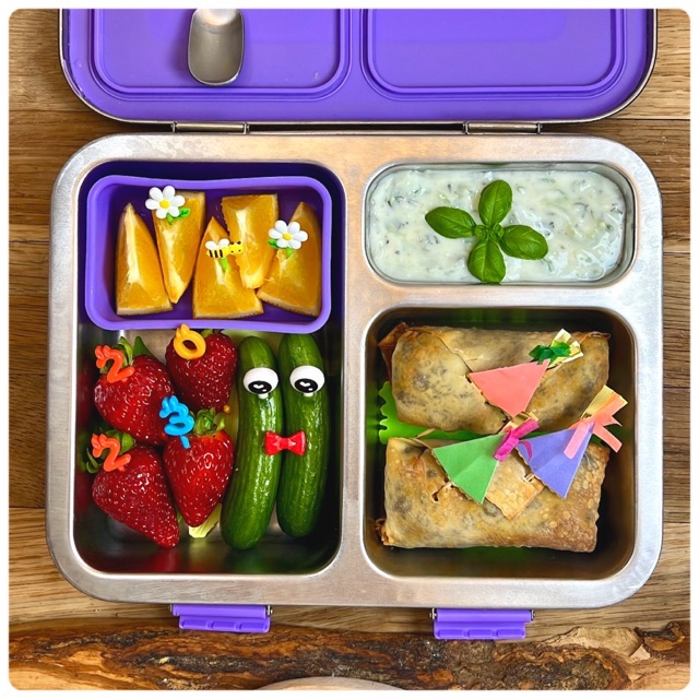 Cucumber yogurt dip with other fresh foods in a kid's Bentgo stainless steel lunchbox