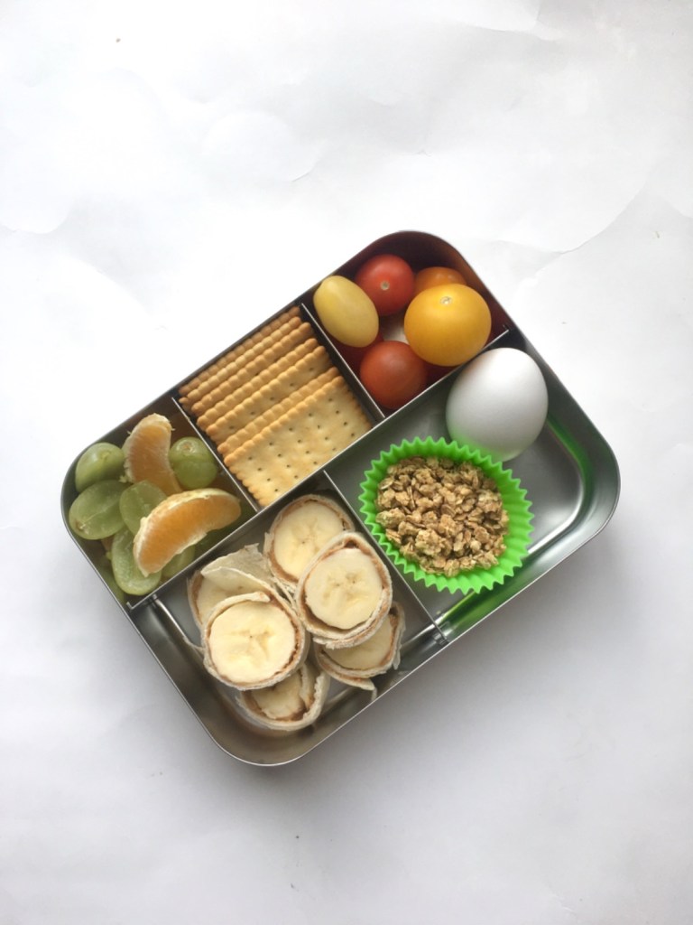 Hard-boiled egg, fruits, crackers in a kid's snack box