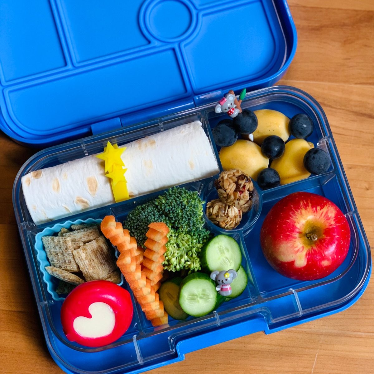 Blue Yumbox lunchbox for kids with a turkey and cheese wrap and fruits and veggies