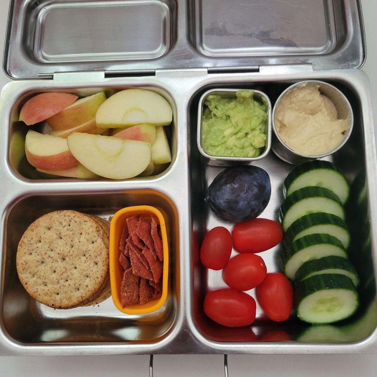 Hummus and veggies for a kid's lunch in a stainless steel Planetbox bento lunchbox