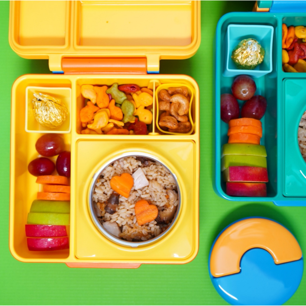 a wonderful lunchbox for her kid, with fried rice, Japanese style, with apple slices, carrot slices, grapes, a Ferrero chocolate candy, and two types of crackers: Japanese crackers and Goldfish crackers!