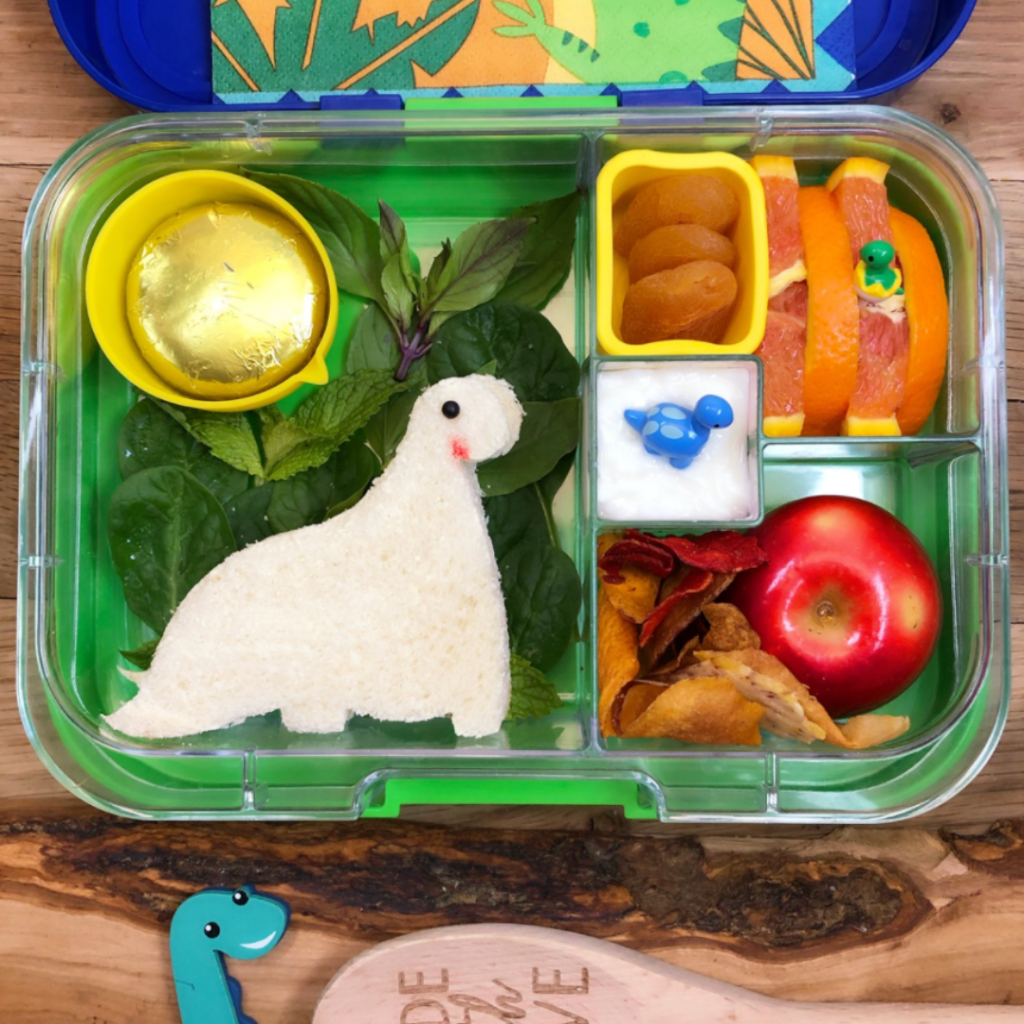 Kid's lunchbox with cute dinosaur-shaped sandwich.