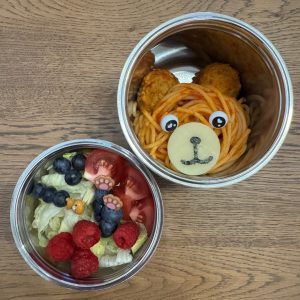 Spaghetti and two meatballs making a bear-shaped face in a thermos for a fun kid's lunch at school.